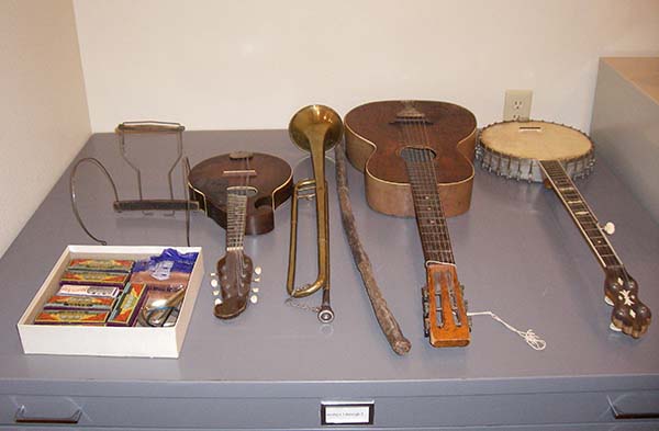 30 Harmonicas, Harmonica Holder behind Mandolin, Bugle, Carved Walking Stick, Guitar and Banjo